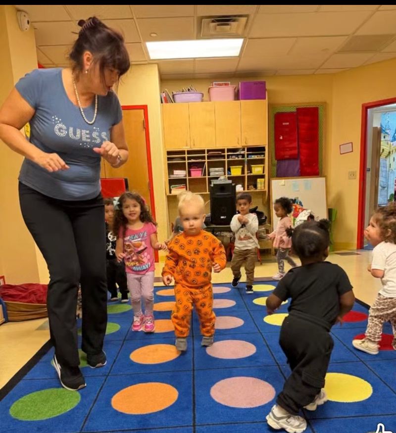 Movement time: a teacher leads the children around the color-spot rug.