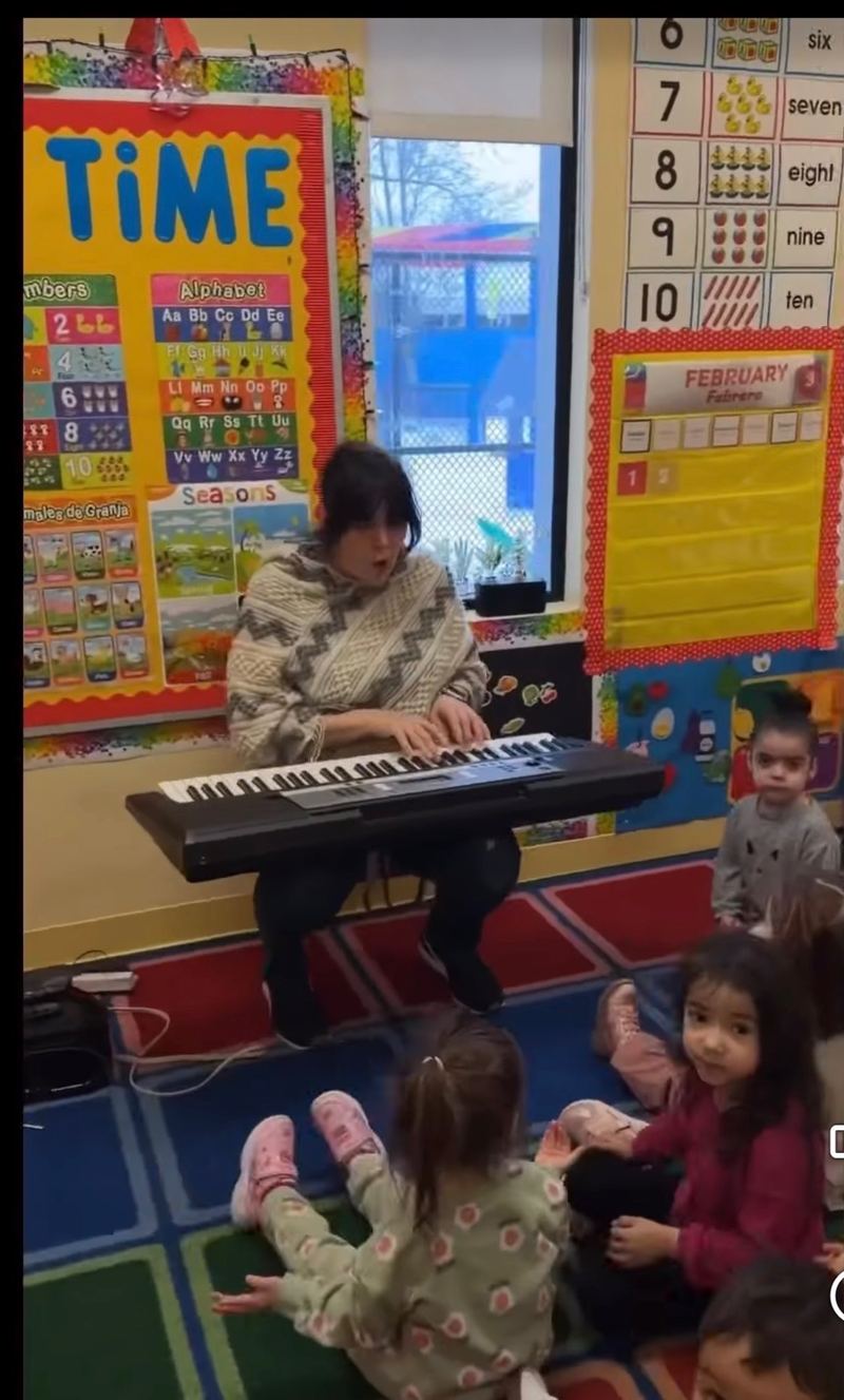 Music time: a teacher plays the keyboard while the children listen on the rug.